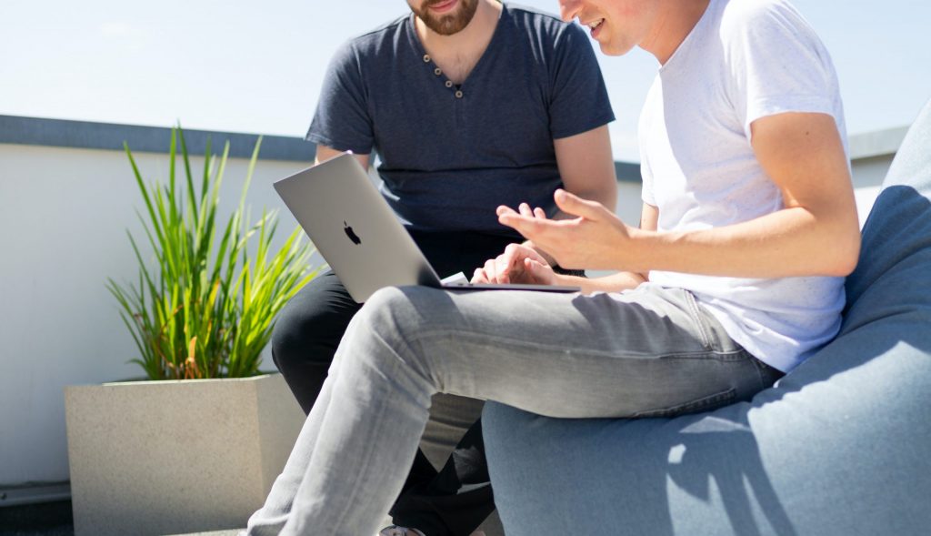 Two Young Men Look at Laptop