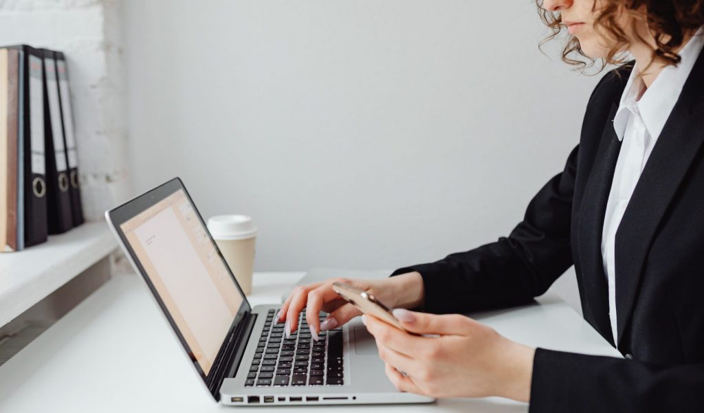 A woman using a laptop and a smartphone at work