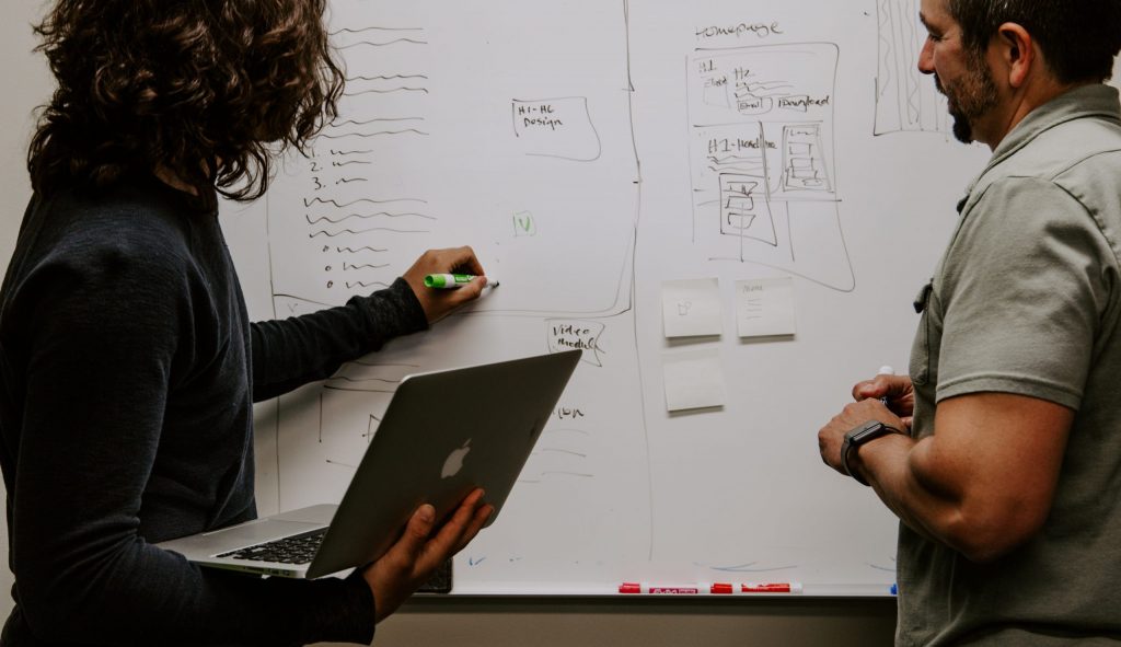 man wearing gray polo shirt beside dry-erase board