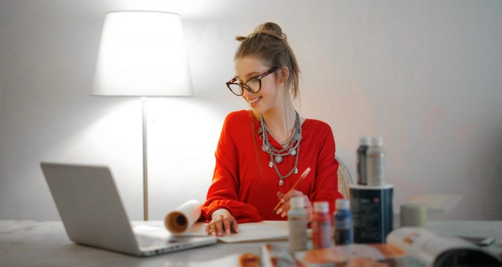 Woman in red long sleeve shirt looking at her laptop