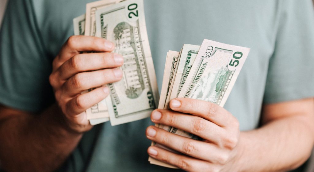 Crop man counting dollar banknotes