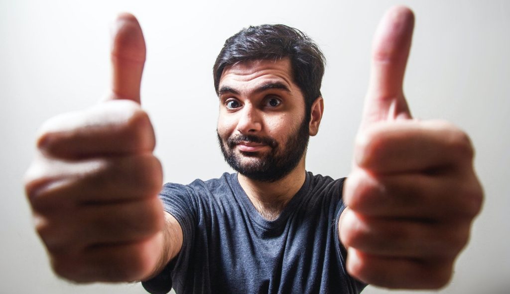 man in gray crew neck shirt making thumbs up