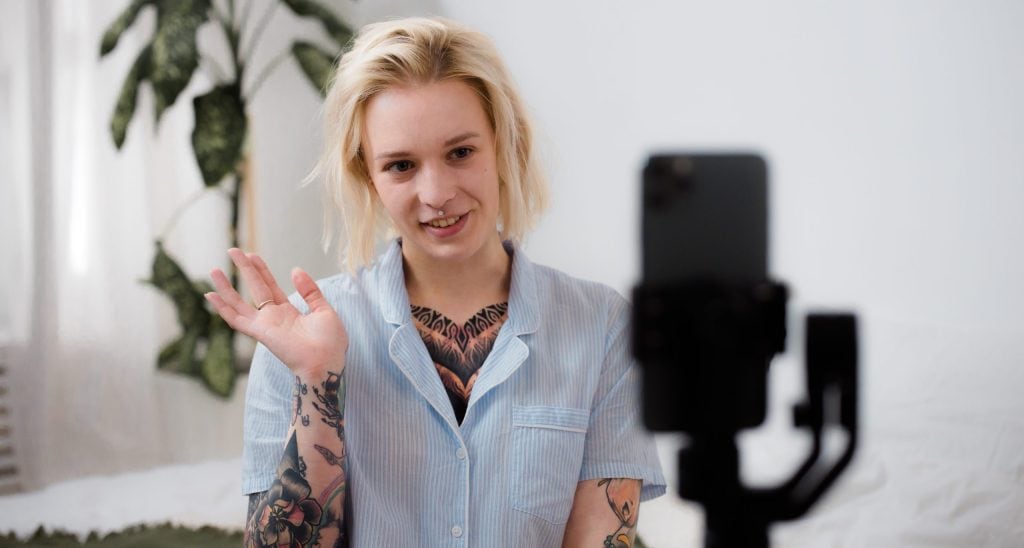 Tattooed woman filming herself with mobile phone